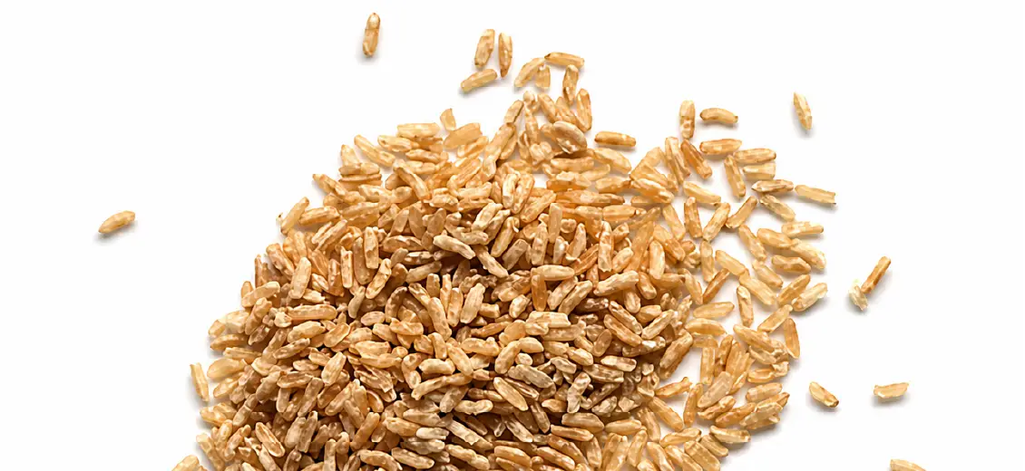 Brown rice scattered on white background.