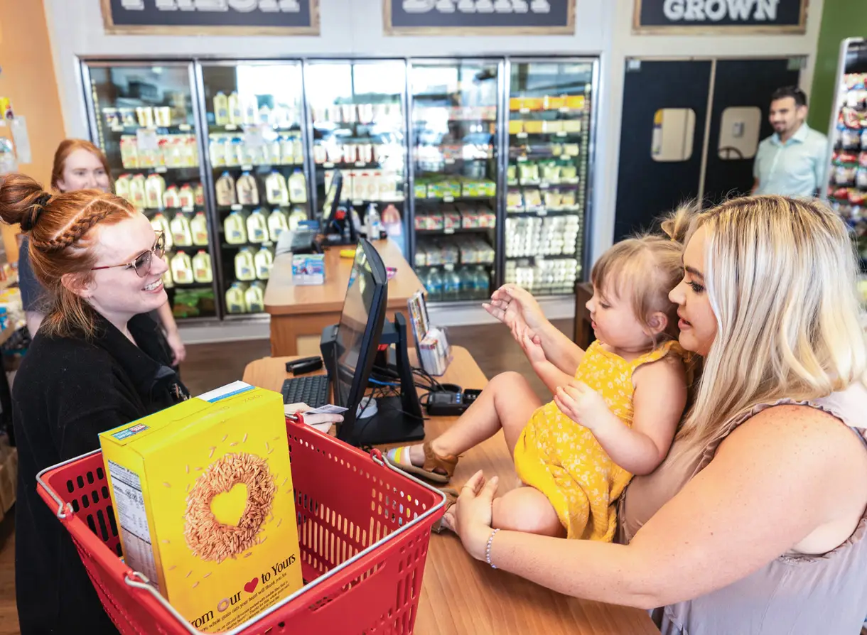Mother and daughter checking out groceries at store.