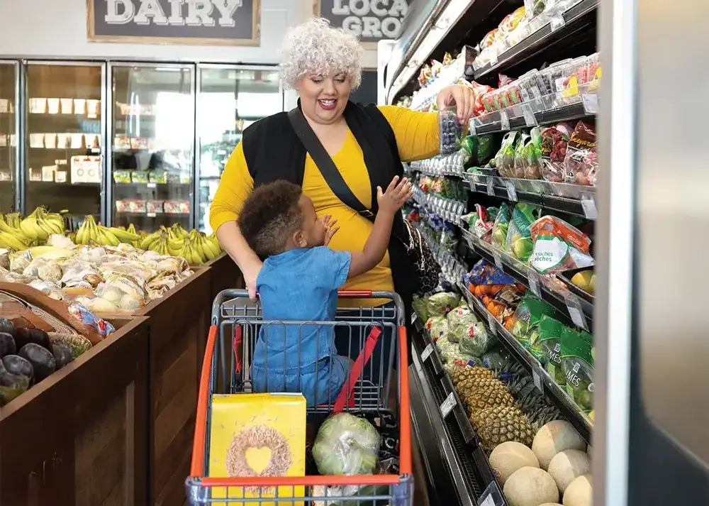 Woman and child grocery shopping in produce aisle.